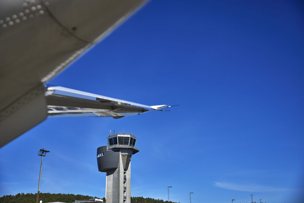 Flytårnet på Kristiansand lufthavn med en flyvinge i forgrunnen.