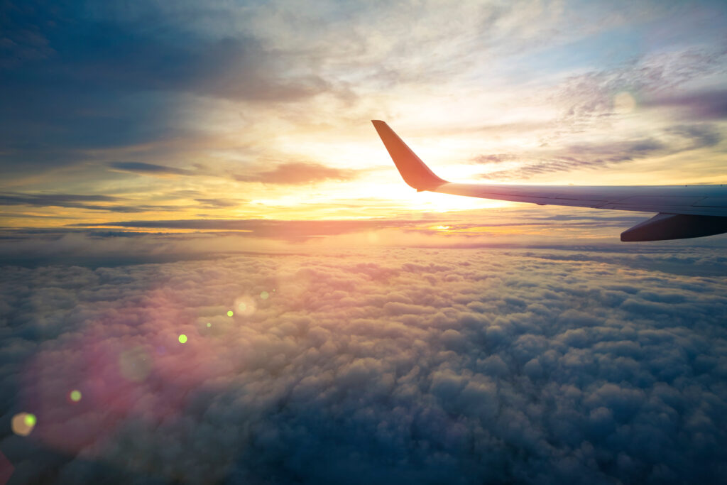 Flyvinge over en skydekt himmel med sollys som skimter gjennom skyene